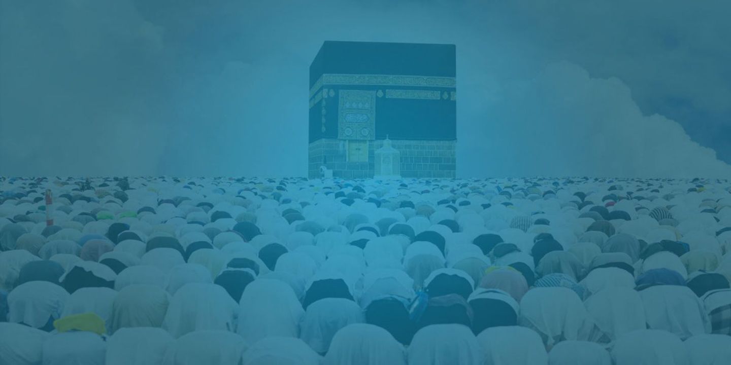 Group of people with bowed heads at the Kaaba in Mecca.